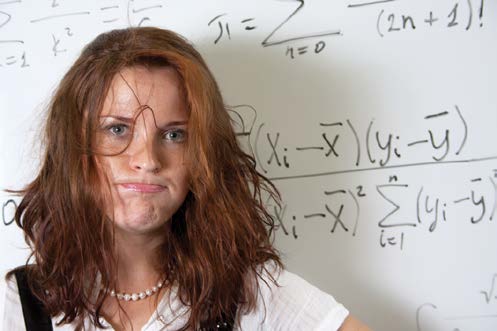 Poczochrana kobieta stoi przed tablicą ze wzorami matematycznymi